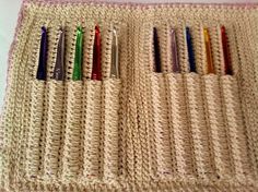 a crocheted place mat with several pens and pencils in each holder on it