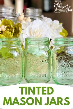 three mason jars with flowers in them and the words, tinted mason jars