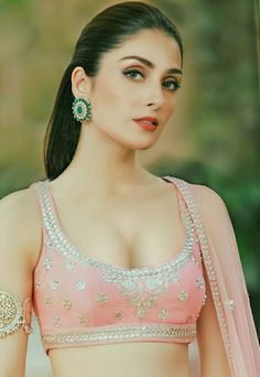 a woman in a pink sari with green earrings on her head and chest, posing for the camera