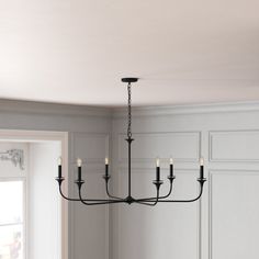 a black chandelier hanging from the ceiling in a dining room with white walls