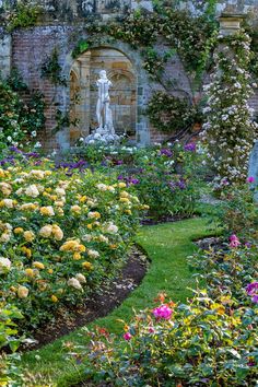 the garden is full of colorful flowers and greenery, with a statue in the background