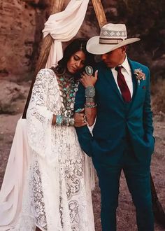 a man in a blue suit and tie standing next to a woman wearing a white dress