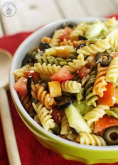 a green bowl filled with pasta salad on top of a red cloth