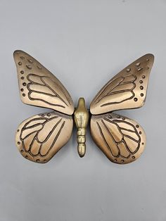 a gold butterfly shaped object on a gray background