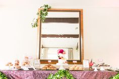 a table topped with cakes and pastries next to a large mirror on top of a wall