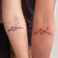 two people with matching tattoos on their arms, one is holding the other's arm