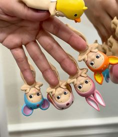 a person is holding several toy figures in their hands, with one finger on the other hand