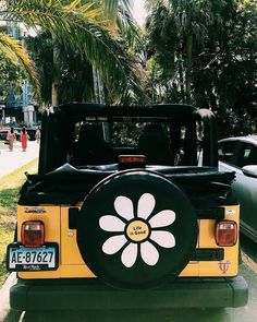 the back end of a yellow jeep with a flower painted on it