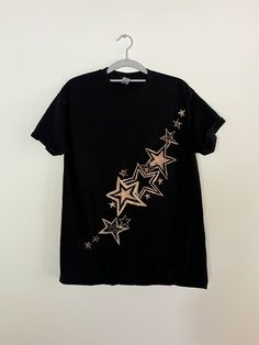 a black t - shirt with gold stars on it hanging from a clothes hanger