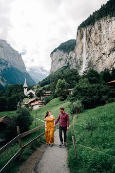 a man and woman walking down a path in the mountains