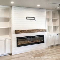 a living room with white bookcases and a fire place in the middle of it