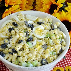 a white bowl filled with pasta salad next to sunflowers