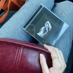 a woman is sitting on the couch with her purse and cd in her lap top