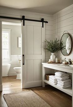 a bathroom with white walls and wood flooring next to a bathtub filled with towels