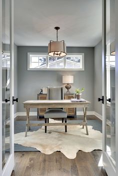 a home office with gray walls and wooden floors, along with a cow hide rug on the floor