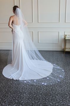 a woman in a wedding dress looking down at the floor with her veil over her head