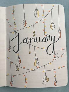 an open notebook with the word january written in black ink and hanging lightbulbs