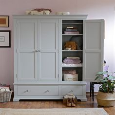 a white armoire in a room with pink walls