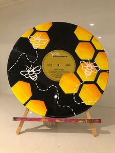 a yellow and black plate with bees on it sitting on top of a wooden stand