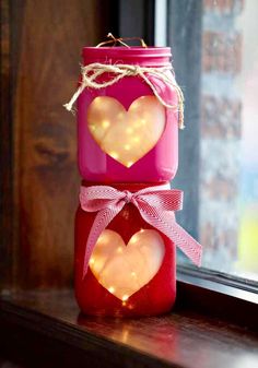 two mason jars decorated with hearts are sitting on a window sill