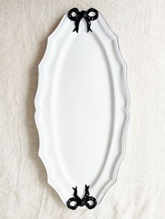 a white plate with black bows on the edge and an oval shaped border around it