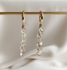 Herkimer crystals measure approximately 7mm drop length: 40mm/1.5″ hoop diameter: 13mm A striking and edgy crystal encrusted statement earring featuring six gorgeous Herkimer diamond quartz crystals.  The crystals are wire wrapped to 14k gold filled bars and suspended from Euro style hoop earrings that latch securely.   All hardware is 14k gold filled.  Herkimer crystals are double pointed resulting in maximum sparkle and shine.   Herkimer "diamonds" are double-pointed quartz crystals affectiona Crystal Cluster Drop Earrings With Sparkling Stones, Single Crystal Earring As A Gift, Sparkling Crystal Dangle Diamond Earrings, Single Long Drop Crystal Earring, Crystal Linear Drop Earrings With Sparkling Stones, Crystal Drop Earrings As A Gift, White Crystal Single Earring, Long Drop Cubic Zirconia Crystal Earrings, Sparkling Crystal Dangle Earrings