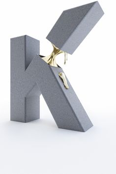 the letter k is made out of concrete and has gold paint dripping from its mouth