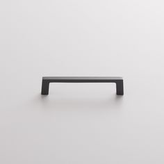 a black cabinet handle on a white wall