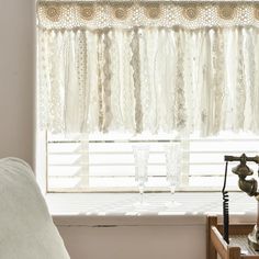 a window with lace curtains and a telephone on the side table in front of it