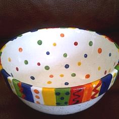 a white bowl with multicolored polka dots on the bottom and letters painted on it