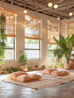 an indoor yoga studio with plants and pillows on the floor, lights hanging from the ceiling