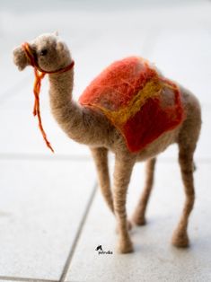 a stuffed camel with a red blanket on it's back