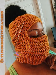 a woman wearing an orange crochet mask with chains on her face and neck