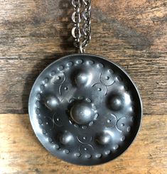 "Vintage pewter pendant necklace by Jorgen Jensen, Denmark. The hand made pendant is round with a nice pattern and raised edges. The diameter measures 2\" / 5cm and the chain measures 36\" / 91cm. Marked: \"PEWTER Jorgen Jensen HANDMADE DENMARK 158\" It's from the 1960's and shows minor wear, such as small scratches, for it's age. Please see all pictures." Silver Pewter Round Pendant Necklace, Pewter Pendant Necklace With Soldered Details, Engraved Round Pendant Medallion Necklace, Silver Pewter Necklace With Round Pendant, Antique Silver Oxidized Round Necklace, Antique Silver Stamped Round Necklaces, Antique Silver Round Necklace With Oxidized Finish, Round Antique Silver Necklace With Oxidized Finish, Symbolic Silver Medallion Necklace With Large Pendant