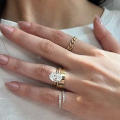 a woman's hand with three different rings on her fingers and one ring in the middle