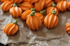 small orange pumpkins sitting on top of a piece of brown paper next to each other