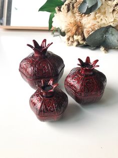 three red vases sitting on top of a white table