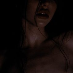 a woman with very large breast and no shirt on is posing for the camera in the dark