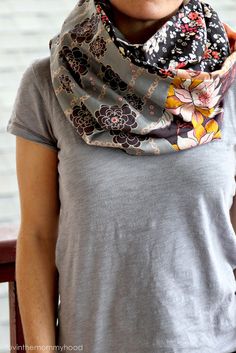 a woman is wearing a gray shirt and a flowered scarf on her neck,