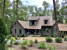 a house in the woods with lots of trees and shrubs around it's front entrance