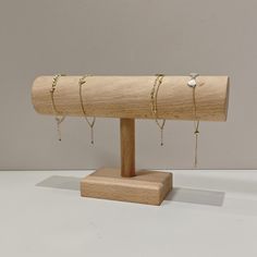 a wooden stand with several rings and chains on it's end, holding a pair of earrings