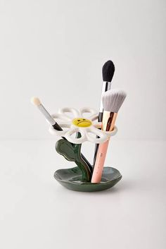 three makeup brushes in a holder on a white surface