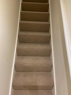 a carpeted staircase leading up to the second floor in a home with white walls and beige carpet