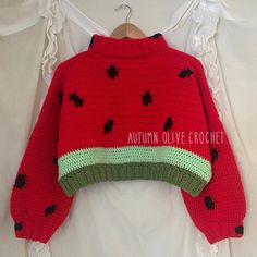 a knitted watermelon sweater hanging on a clothes hanger