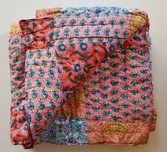 a pink and blue patchwork quilt with flowers on it's side, folded in half