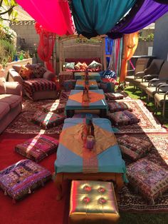 an outdoor area with tables, couches and rugs