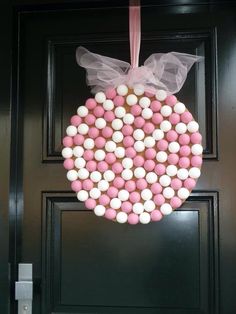 a wreath made out of candy balls hanging from a front door with a bow on it