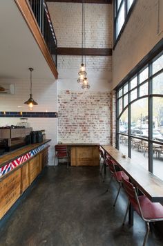 the interior of a restaurant with tables and chairs in front of a brick wall that has multiple windows