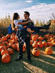 a man carrying a woman on his back in front of pumpkins