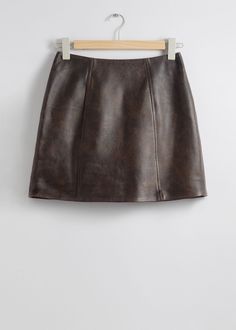 Sleek Leather Mini Skirt A classic, high-waisted mini skirt crafted from genuine cowhide leather. Featuring a clean, minimalist design with a back zipper closure. Detailed and Descriptive: Luxurious high-waist leather mini skirt Indulge in timeless elegance with our premium leather mini skirt. The high-waist silhouette flatters your figure while the clean lines create a sophisticated look. Crafted from genuine cowhide leather and fully lined for comfort. Emphasizing Quality and Craftsmanship: Pr Luxury Classic Mini Skirt For Women, Luxury Brown Mini Skirt, Luxury Classic Mini Skirt, Luxury Sleek Mini Skirt For Women, Skirt For Fall, Applique Blouse, Brown Leather Skirt, Brown Mini Skirt, Waistcoat Dress